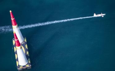 Ein Sportflugzeug fliegt zwischen zwei Pylonen und hinterlässt lange Rauchspur
