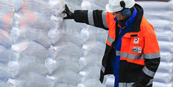 Arbeiter vor gestapelten Plastiksäcken
