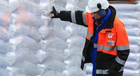TOTAL Arbeiter vor gestapelten Plastikbeuteln
